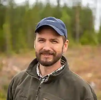 Martin Holmgren in a forest with a smile on his face.